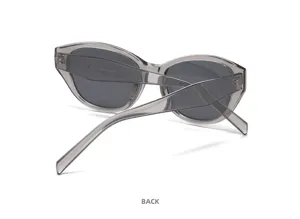 Occhiali da sole cat-eye alla moda con montatura grande, dettaglio occhiali grigi trasparenti.