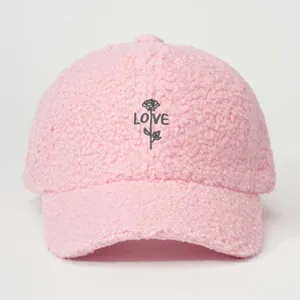 Close-up of pink faux shearling baseball cap detail, featuring delicate rose and love embroidery.