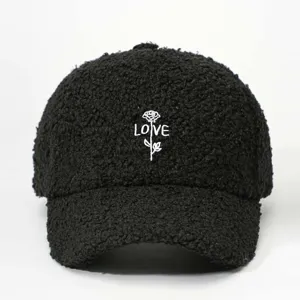 Close-up detail of black sherpa baseball cap with white rose and love embroidery motif.