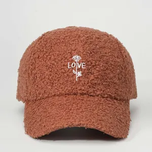Detailed view of brown sherpa baseball cap with white embroidered rose and love text.