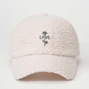Close-up detail of cozy faux shearling baseball cap featuring embroidered rose and love text.