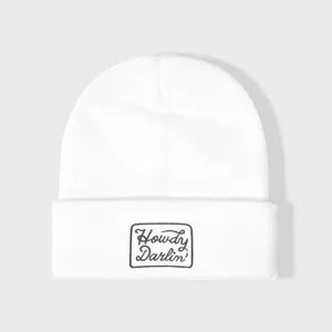 Witte gebreide muts met geborduurd tekstdetail aan de voorkant, warm en casual winteraccessoire.