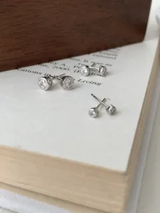 Detailansicht von silbernen Ohrringen mit runden Zirkonia-Steinen und glänzender Oberfläche.