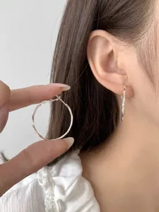 Close-up detail of sterling silver hoop earrings worn on ear, simple and delicate design.