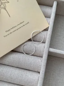 Gros plan de délicates bagues vagues texturées en argent sterling S925 dans un écrin.