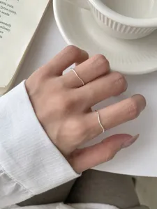 Gros plan de bagues en argent ondulées minimalistes portées sur la main, design empilable.
