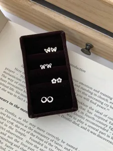 Vue détaillée de boucles d'oreilles papillon et fleur en argent sterling dans un coffret velours.