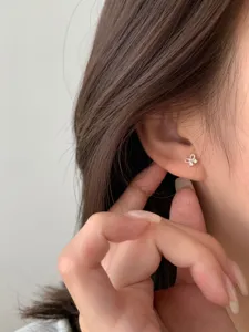 Gros plan détaillé de boucles d'oreilles nœud délicates portées à l'oreille, bijou élégant.