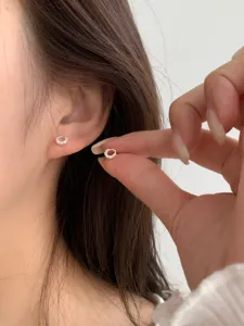 Gros plan détaillé de boucles d'oreilles clous rondes en argent pavées de cristaux.