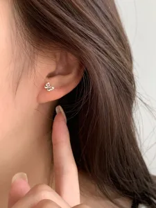 Gros-plan des boucles d'oreilles nœud argenté délicates portées à l'oreille, bijou chic.