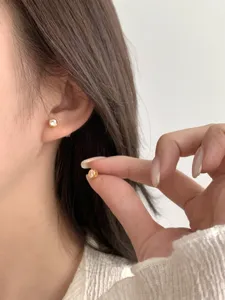 Detailansicht minimalistischer runder Diamant-Ohrstecker am Ohr mit feinem polierten Finish.