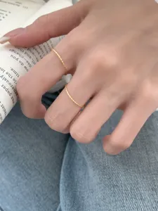 Detailopname van minimalisten ultra-dunne getwiste stapelringen gedragen aan de vingers.