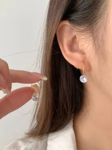 Nahaufnahme von minimalistischen Einzel-Diamant-Ohrringen, funkelnder Zirkon in Gold.