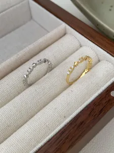 Dettaglio di anelli con cuore in argento S925 e zirconi in portagioie di legno, gioiello elegante.