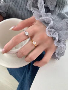 Gros plan de bagues élégantes en argent et or avec oxyde de zirconium en poire.
