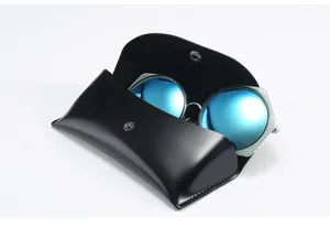 Étui à lunettes en cuir noir portable avec lunettes de soleil tendance à verres bleus.