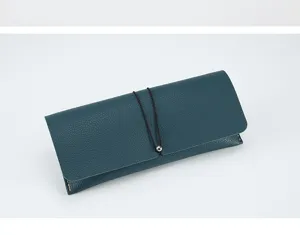 Dark blue leather glasses case detail showing fine texture, elastic cord, and metal bead.