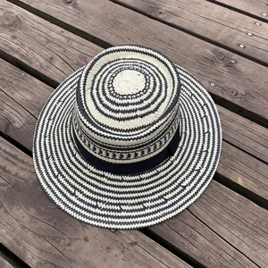 Close-up detail of the black and white woven pattern and fine straw texture of the summer hat.