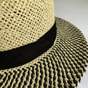 Close up view of vintage woven straw hat texture showing black ribbon and beige black brim details.