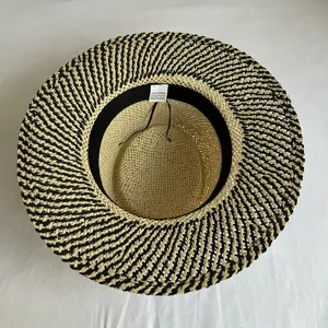 Detailed view of a black and white woven straw flat top hat interior, summer beach sun protection.