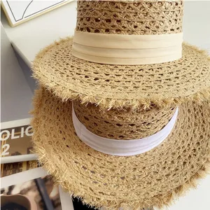 Primer plano detallado de sombreros de paja de rafia de verano con flecos y cinta.