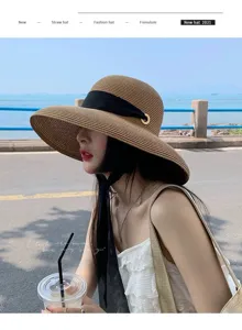 Elegante cappello di paglia da donna a tesa larga con nastro nero per la spiaggia estiva.