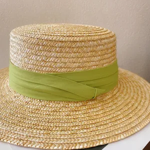Classic straw boater hat with green ribbon, perfect detail view for summer beach sun protection.