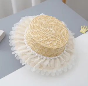 Gedetailleerde close-up van de kinderstrohoed met platte top, parels en mooie tule volant.
