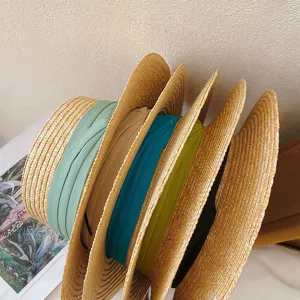 Close-up detail of vintage flat top straw hats with colorful ribbons, woven straw texture.