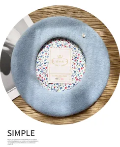 Primer plano detallado de boina de lana azul claro con forro floral y detalle metálico.