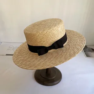 Detailansicht eines handgemachten Strohhuts mit schwarzer Schleife, eleganter Sonnenschutz.