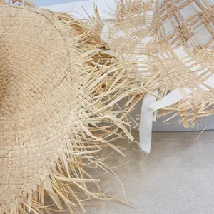 Nahaufnahme des Raffia Fransen Sonnenhuts für Damen, mit natürlicher Stroh-Textur.
