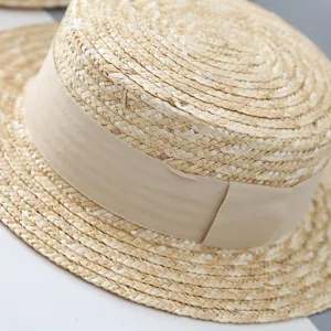 Primer plano detallado de la textura de paja tejida y la cinta beige en sombrero de verano.