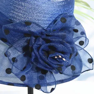 Close-up detail of blue organza sun hat with black polka dots and large flower decor.