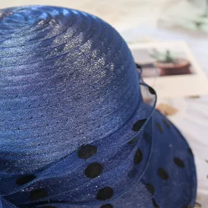 Close-up detail of dark blue sheer organza sun hat with black polka dots and shiny threads.