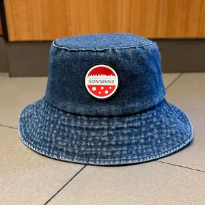 Λεπτομερής όψη σκούρου μπλε τζιν καπέλου bucket με στρογγυλό λογότυπο Sunshine.
