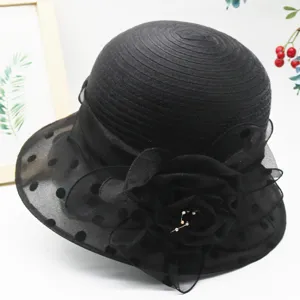 Detailed view of black organza polka dot sun hat with large floral accent and brooch.