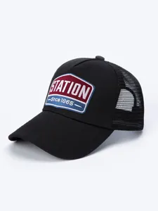 Λεπτομερής κοντινή άποψη μαύρου καπέλου trucker με κομψό vintage κεντημένο σήμα.