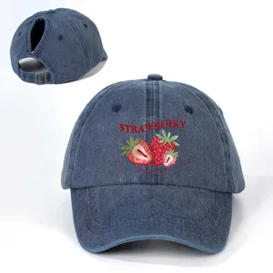 Distressed denim ponytail baseball cap with strawberry print and adjustable back strap.
