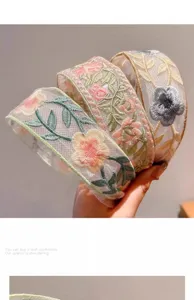 Detail shot of exquisite mesh floral embroidered headband, showing intricate fabric texture.