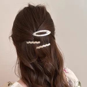Detailed view of three iridescent acetate hair clips styling on wavy brown hair gracefully.