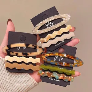 Detail view of acetate hair clips set featuring elegant oval and wavy side hairpins.