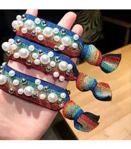 Primo piano di elastici per capelli arcobaleno decorati con perle finte e sfere argentate.