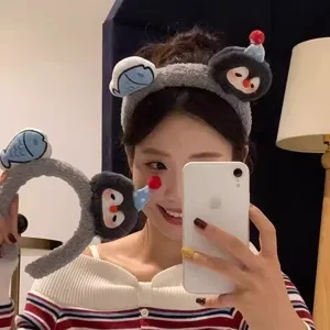 Gedetailleerd uitzicht op zachte pluche pinguin en vis haarband, leuke cartoon accessoire.