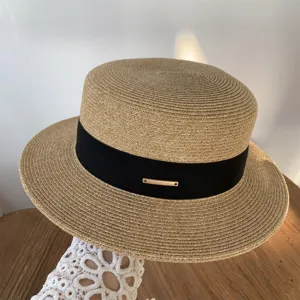 Moderno y elegante sombrero de paja plano con cinta negra y detalle metálico veraniego.