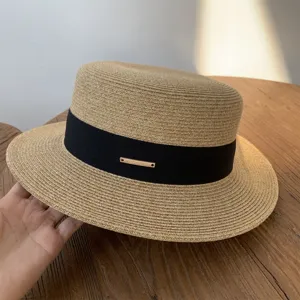 Vista detallada del sombrero de paja para mujer con parte superior plana, cinta negra y metal.