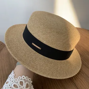 Vista detallada del sombrero de paja elegante con cinta negra y detalle metálico chic.
