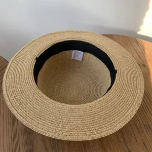 Sombrero de paja plano minimalista con trenza fina, ideal para playa de verano y protección.