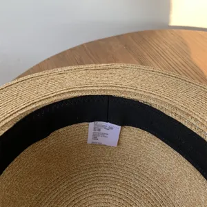 Vista detallada del interior del sombrero de paja con textura trenzada y etiqueta de cuidado.