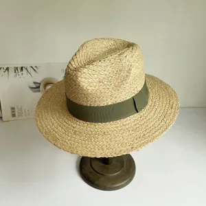 Nahaufnahme eines handgeflochtenen Bastsonnenhuts mit grünem Band auf Ständer für Sommer.